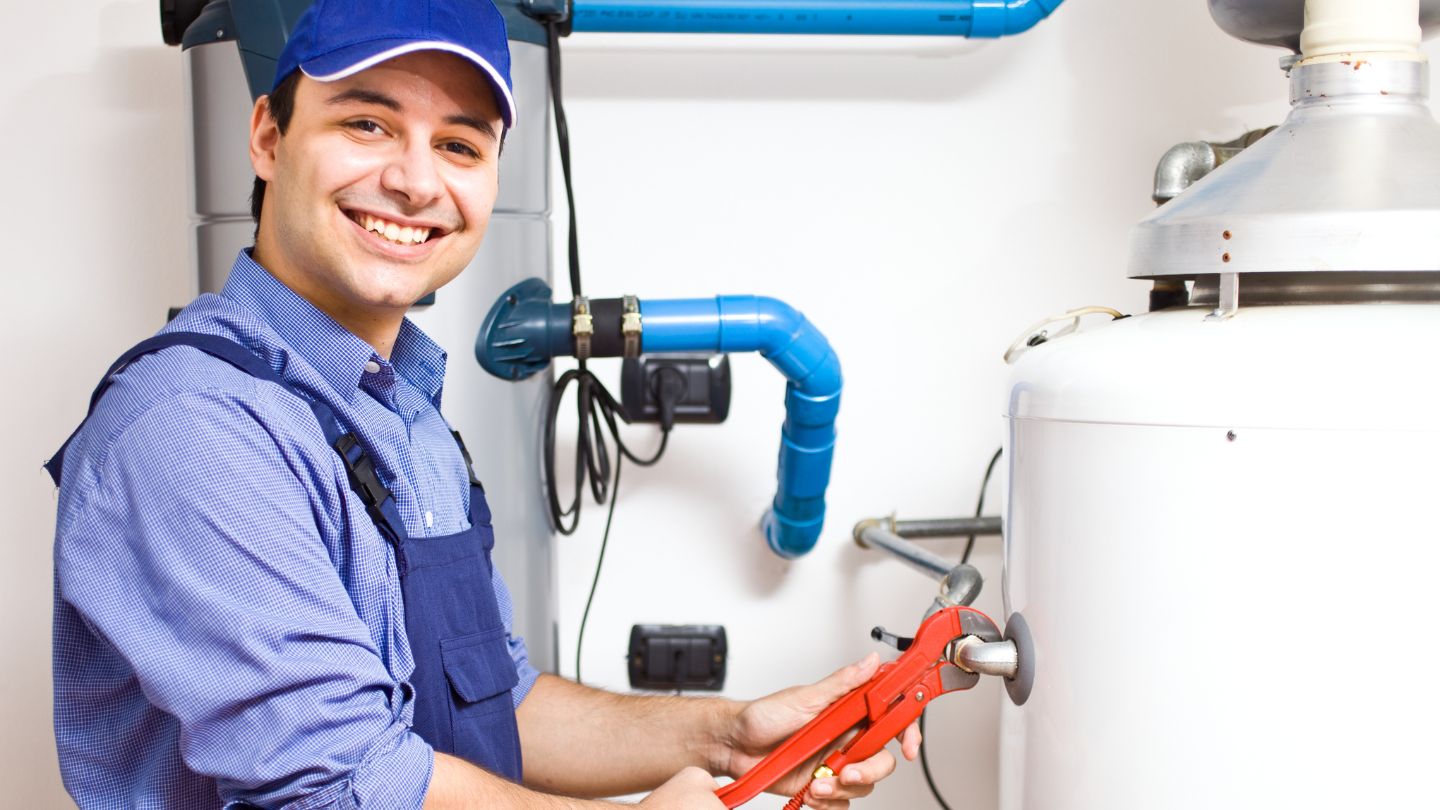 water heater technician smiling while looking for signs of water heater failure