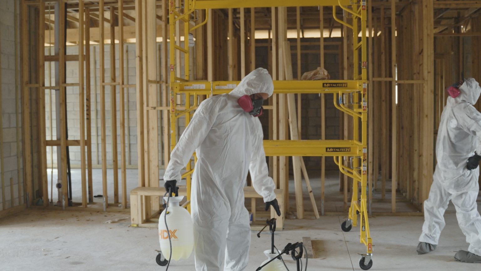 United Water Restoration Group technicians in protective suits treating mold inside a home